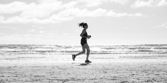 A woman jogging on La Lucila del Mar beach, Argentina in a monochrome setting. Capturing fitness and freedom.